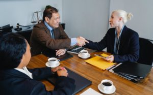 cheerful colleagues shaking hands after deal